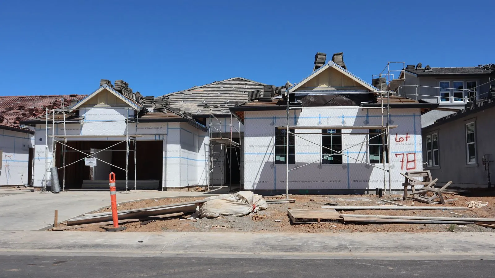 Front view of a single-family home under construction with scaffolding and materials.